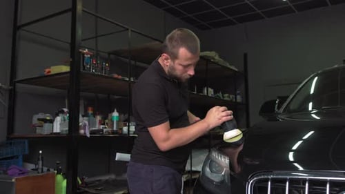 Man Polishing Car with Polisher in Garage