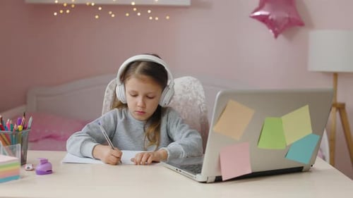 Young Child Doing Homework at Desk With Laptop