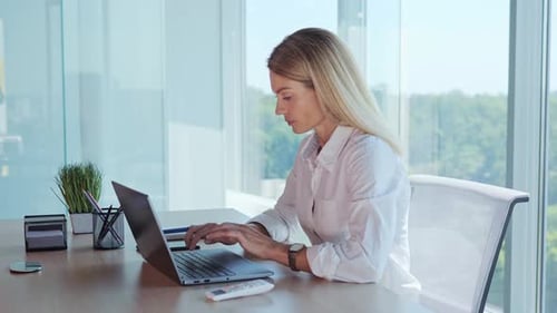 Woman Typing on Laptop in Modern Office