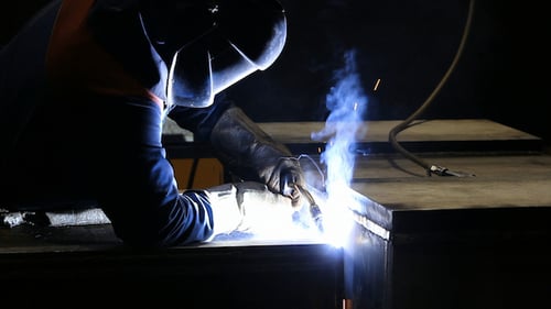Welder at Work with Sparks Flying in Factory