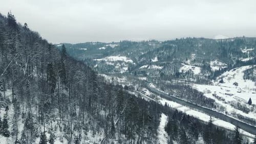 Winter River Flowing Through Snow-Covered Mountains Aerial