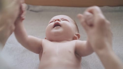 Baby Lying in Crib with Hands Held