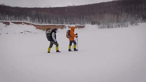 Hikers Trekking Across Snowy Field in Winter