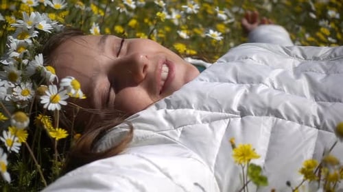 Smiling Woman Lying in Field of Daisies