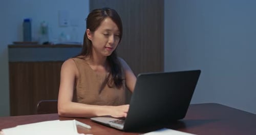 Woman Working on Laptop at Desk at Night