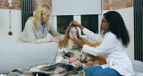 Une femme médecin aide une mère attentionnée à mettre le nébuliseur sur la tête de sa fille