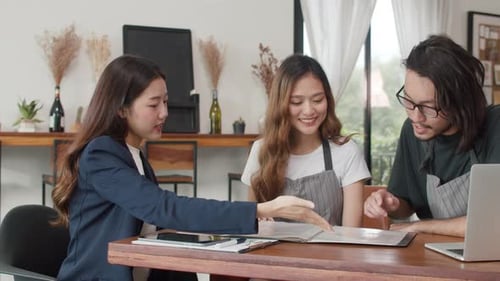 Asian small business owners couple meeting with consultant taking plan and finance in cafe.