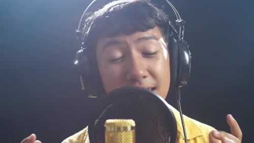 Young Adult Sings into Microphone in Studio