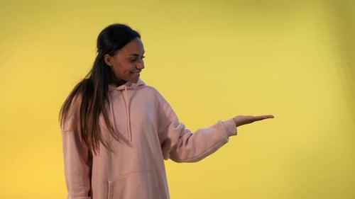 Smiling Woman Presenting on Yellow Background