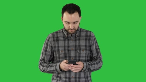 Young man walking and using a smartphone on a Green Screen