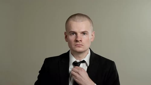 Man in Suit Straightens Tie Getting Ready