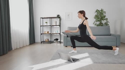 Woman Stretching and Exercising with Online Laptop Class