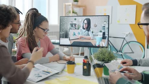 Men and Women Talking To Female Colleague Online Through Video Call in Office