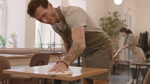 Man Cleaning Table in Cafe