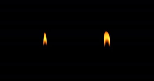 Two Candle Flames Flicker Intensely Against Black