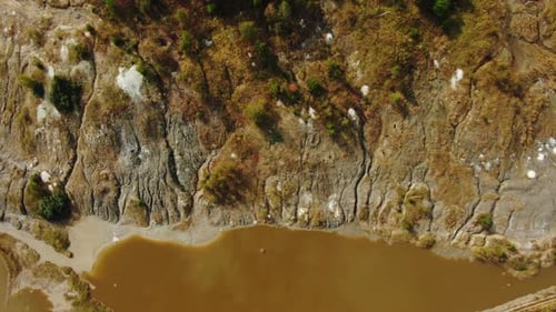 Von oben Luftaufnahme des kleinen schlammigen Sees in der Nähe eines rauen Abhangs der Bergkette auf dem Land