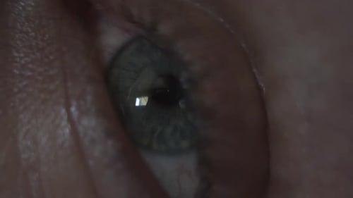 Macro close up of a man's eye opening, looking around, and looking at his phone.