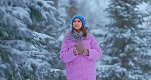 Jolie fille se promène dans la forêt d'hiver, les pins sont dans la neige