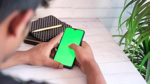 Rear View of Young Man Using Smart Phone Indoor