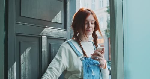 Smiling Woman Listens to Music on Smartphone Indoors