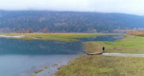 Lone Man Walking with Dog Toward Canoe by Lake