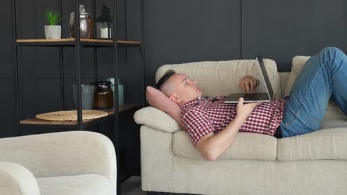 Adult Lying on Couch Using Laptop Indoors