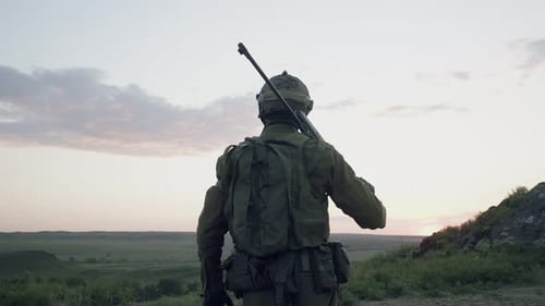 Soldier Standing on Hilltop at Sunset