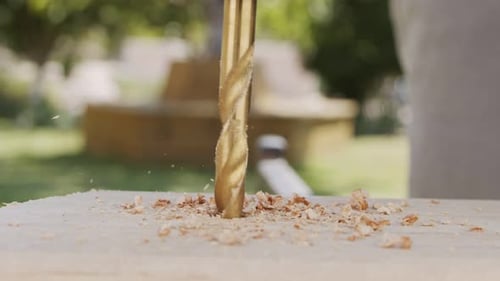 Close up of a drill making a hole in a piece of wood - slow motion