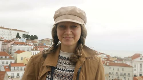 Une femme pose sur une terrasse d'observation contre des bâtiments lumineux