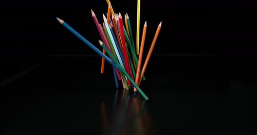 Colored Pencils Falling onto Black Reflective Surface