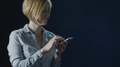 Woman Using Mobile Phone Against Dark Background