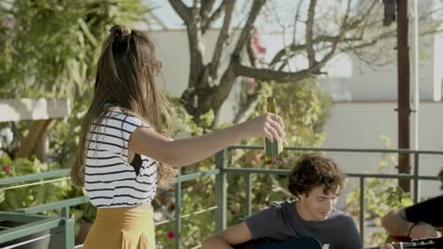 Young Woman Dances as Friends Play Guitar Outside