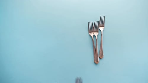 Hand Arranging Forks and Knives on Table