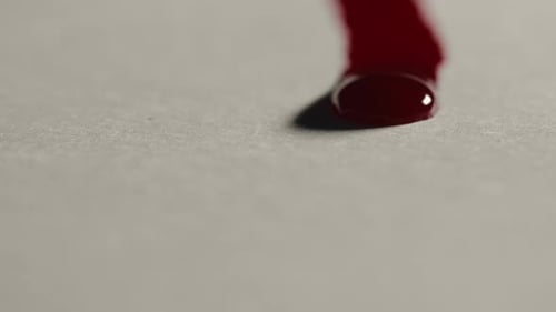 Thick Red Liquid Pouring Onto Gray Surface