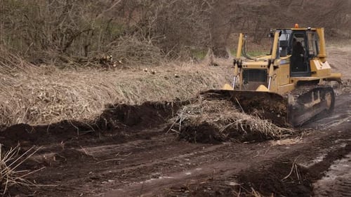 Bulldozer at Construction Site Shovels Soil Into a Heap