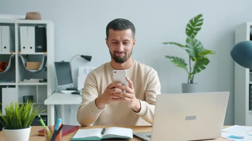 Carefree Middle-aged Man Using Smartphone Smiling Working in Office at Work