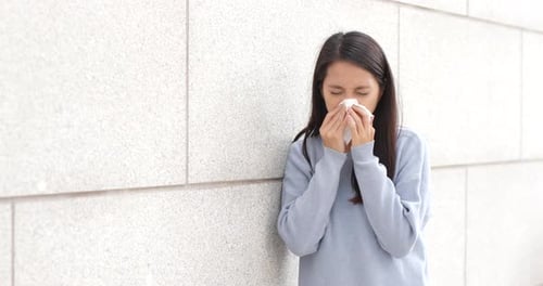 Woman sneezing at outdoor