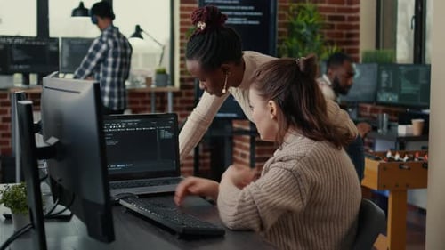 Two Software Coders Analyzing Source Code Looking for Errors Running on Laptop Screen