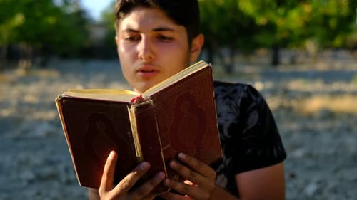 Junger Mann liest Koran im Freien