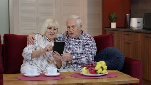 Elderly Couple Using Tablet Together on Couch