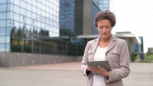 Professional Woman Uses Tablet Outside Office Building