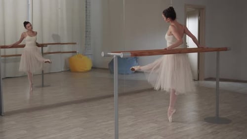 Elegant Ballerina Stretching at Barre in Dance Studio