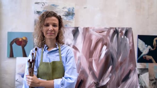 Artist in Studio with Brushes and Finished Paintings