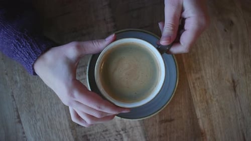 Woman Stirring Coffee In Cafe