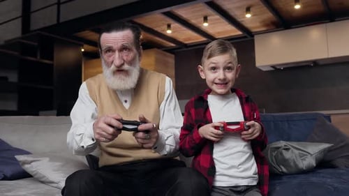 Grandfather and Grandson Playing Video Games Together at Home