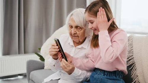 Senior Woman and Child Using Phone Together Indoors