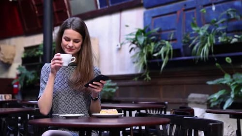 Beautiful Woman Using Phone In Cafe, Drinking Coffee