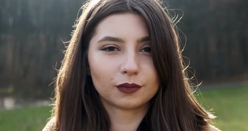 Portrait of Young Attractive Female Who Smiling and Looking at the Camera on Green Lawn. Cheerfully