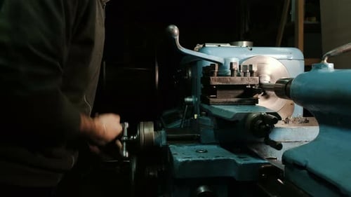 Man Operates Lathe Shaping Metal Piece