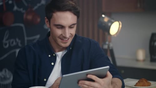 Smiling Man Checks Tablet in Kitchen